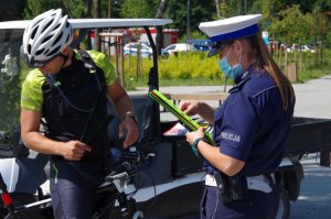 policjanci rozdają opaski odblaskowe, kolorowanki i koszulki w ramach prowadzonej akcji