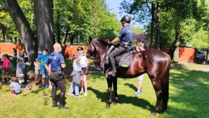 policjant na koniu służbowym, stoi przed grupą dzieci i rozmawia o bezpieczeństwie