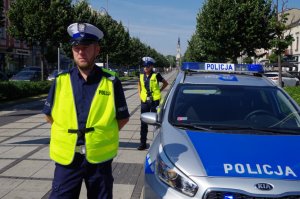 policjant stoi przy radiowozie-w tle Jasna Góra