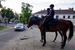 policjanci na koniach stoją przed parkiem jasnogórskim w tle radiowóz