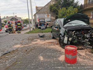 uszkodzony pojazd renault w wyniku kolizji, na drodze samochód straży pożarnej, a w pobliskim budynku wbity samochód marki audi