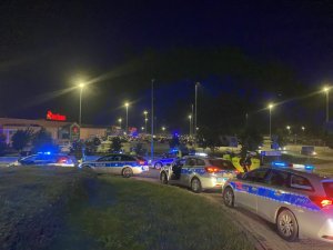 policjanci stoją przy samochodach i kontrolują stan trzeźwości kierujących wyjeżdżających z parkingu