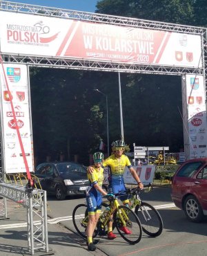 kobieta i mężczyzna w stroju kolarskim na rowerach pozują do zdjęcia obejmując się