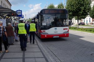 policjanci idą w kierunku autobusu, który zatrzymał się na przystanku