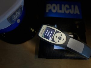 alcosensor położony na okładce z napisem Policja, obok czapka policjanta z ruchu drogowego