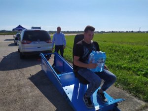 uczestnik siedzi ze zgrzewką wody na kolanach i zjeżdża na symulatorze zderzeń