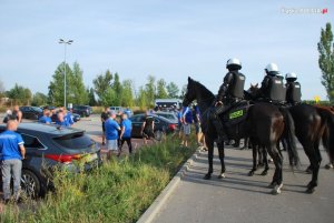 policjanci na koniach służbowych obserwują grupę pseudokibiców