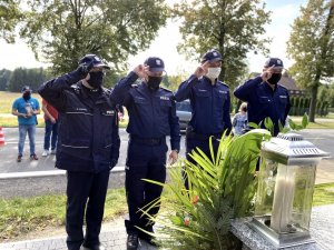 czterech policjantów w mundurach stoi przed grobem starszego posterunkowego Krzyżanowskiego i oddaje honor