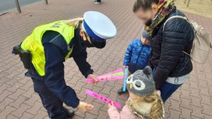 policjantka wręcza odblaski dwójce dzieciom i kobiecie