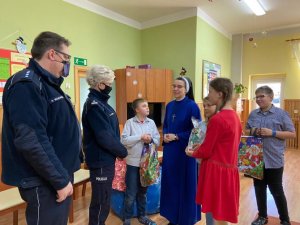 siostra zakonna wraz z dziećmi wręcza świece w kształcie choinki w ramach podziekowania dla policjantów.