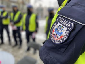 policjanci z ruchu drogowego w tle na pierwszym planie naszywka na mundurze z napisem Ruch Drogowy