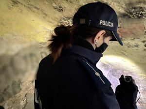 policjantka kontroluje pustostan trzymając latarkę w ręce
