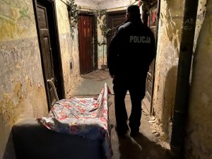 policjant idzie korytarzem w bloku mieszkalnym