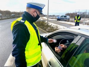 policjant podczas kontroli pojazdu odbiera dokumenty od kierowcy