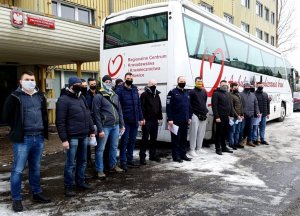 nieumundurowani policjanci pozują do zdjęcia przed ambulansem