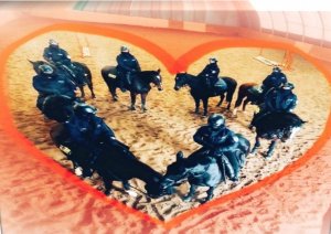 8 policjantów na koniach ustawieni w kształcie serca, wokół namalowany czerwony kontur serca