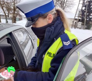 policjantka przekazuje kierowcy siedzącemu w samochodzie naklejki