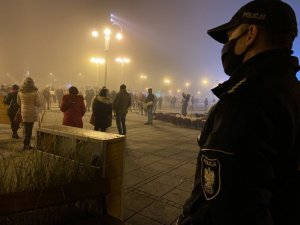 policjant podczas zabezpieczenia zgromadzenia na pierwszym planie, w tle osoby biorące udział w zgromadzeniu na Placu Biegańskiego w Częstochowie