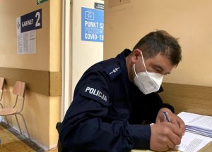 policjanci wypełniają kwestionariusze przed sczepieniem przy stoliku