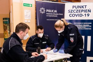 policjanci wypełniają kwestionariusze przed sczepieniem przy stoliku