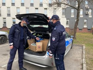 umundurowani policjanci pakują do bagażnika zebraną odzież