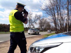 policjant przy drodze z fotoradarem w ręce