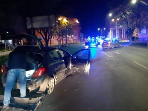 ulica nocą, mężczyna, który stoi przy samochodzie , w tle radiowozy z niebieskimi sygnałami