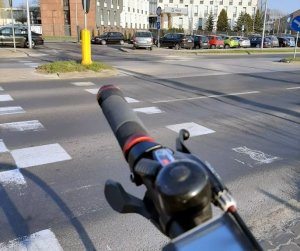 rączka roweru na tle drogi, w tle budynek Komendy Miejskiej Policji w Częstochowie