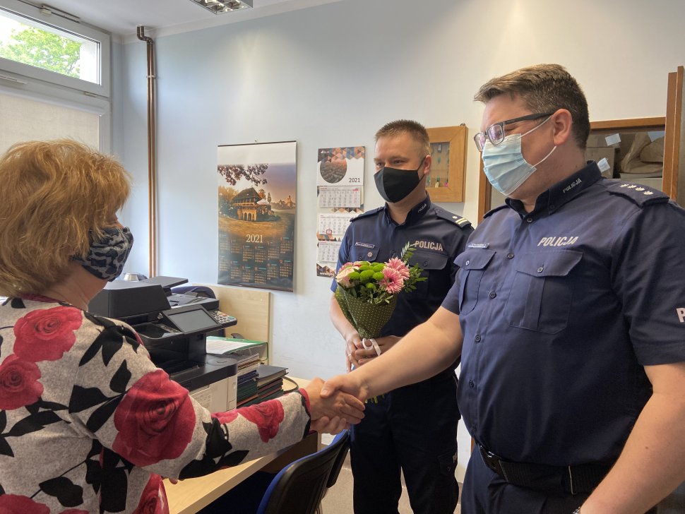 dwóch policjatnów wręcza kwiaty kobiecie