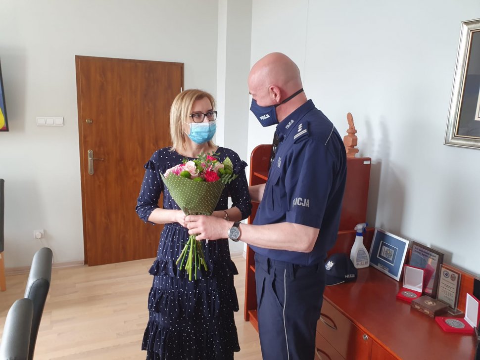 policjant wręcza kwiaty kobiecie