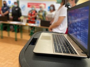 ekran laptopa, na którym wyświetleni są uczestnicy, w tle komisja