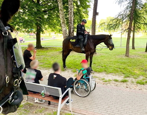 policjant na koniu legitymuje siedzących na ławce mężczyzn