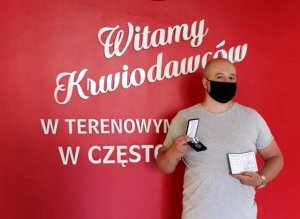 policjant pozuje z orderem na tle napisu witamy krwiodawców