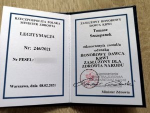 legitymacja otwarta i wpisane dane policjanta oraz numer legitymacji i nazwa odznaczenia