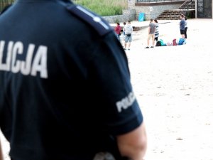 koszulka z napisem policja, w tle grupa osób na plaży