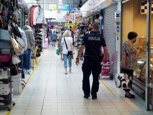 policjanci w mundurach kontrolują sklepy - spacerują alejkami sklepów z regałami, na których stoi towar