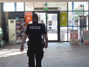 policjanci w mundurach kontrolują sklepy - spacerują alejkami sklepów z regałami, na których stoi towar