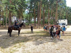 policjanci na koniach stoją przed grupą dzieci i młodzieży na podwórku