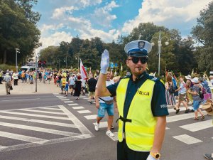 policjanci w kamizelkach odblaskowych kierują ruchem przy przejściu dla pieszych, w tle pielgrzymi