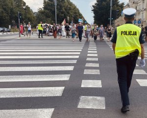 policjant przechodzi przez przejście dla pieszych, na wprost stoją pielgrzymi
