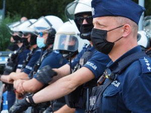 policjanci stoją w szeregu podczas zabezpieczenia, patrzą przed siebie