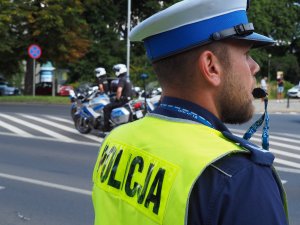 policjant z ruchu drogowego stoi przy ulicy, w tle policjanci na motocyklach