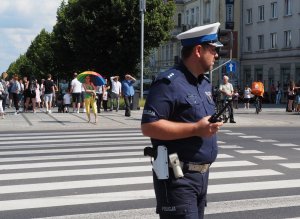 policjant z ruchu drogowego stoi na pasach i trzyma w ręku radiostację