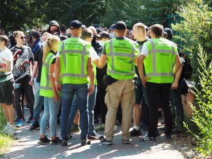 policjanci w zielonych odblaskowych kamizelkach rozmawiają z grupą osób