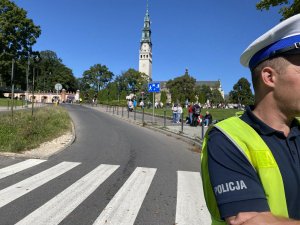 policjant z ruchu drogowego stoi przy przejściu dla pieszych, w tle Jasna Góra