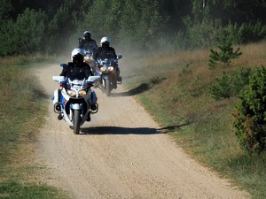 policjanci na motocyklach jadą gruntową drogą
