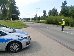 policjant stoi na pasie ruchu z tarczą do zatrzymywania pojazdu i daje znak kierującemu busem do zatrzymania