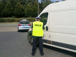 policjant podczas rozmowy z kierowcą białego samochodu dostawczego