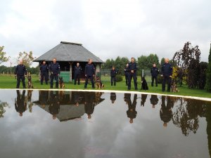 policjanci ustawieni w dwóch szeregach pozują do zdjęcia na tle zbiornika wodnego