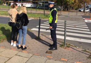 policjant przed przejściem dla pieszych rozmawia z 2 dziewczynami